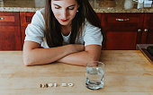 Woman with a row of vitamins tablets and and pills at home with a glass of water nutritional supplements