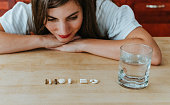 Woman with a row of vitamins tablets and and pills at home with a glass of water nutritional supplements