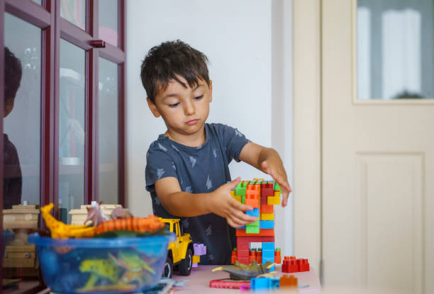 istock Cute little boy playing with colorful plastic blocks at home 1614822265