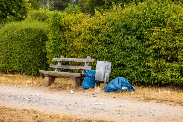 istock Litter and garbage bags next to a trash can at a park bench 1614833047