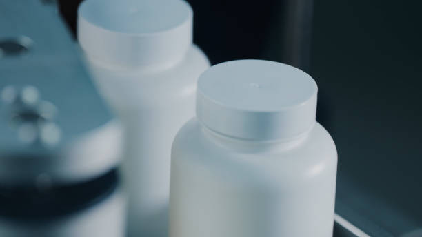 istock 4K Plastic bottles with white plastic caps moves to the packing on the pharmaceutical production line. Jars move in a row on a conveyor in a manufacturing plant. Conveyor Provides Automated Processes 1614843825