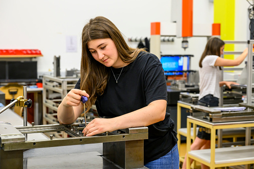 Young woman with blank expression screwing in a workshop