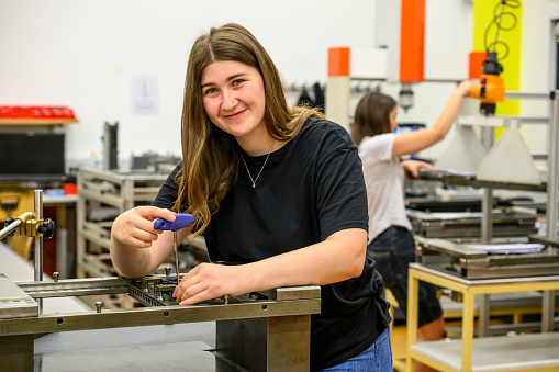 Happy young woman screwing in a workshop looking at camera