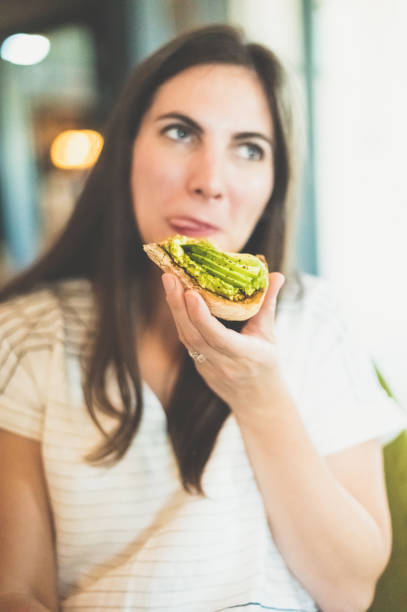 istock Millennial woman eats an open faced avocado toast sandwich 1614856558