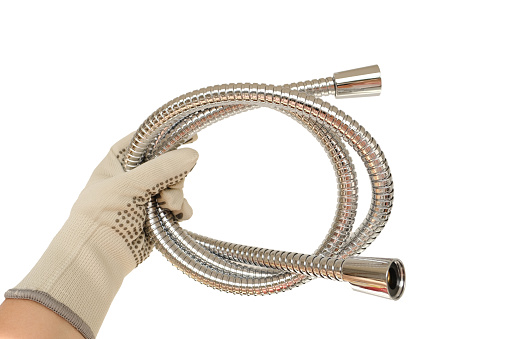 close-up of new metal stainless steel shower hose with double linkage in hand in glove, anti-twist, concept hygienic shower, locksmith work