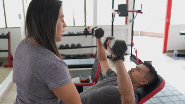 Female fitness instructor helping her student in the gym