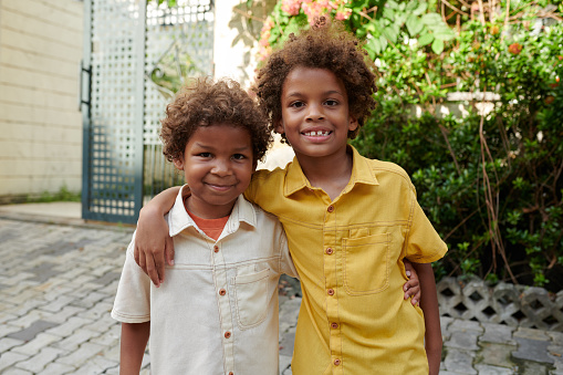 Portrait of hugging brothers standing in backyard and smiling at camera