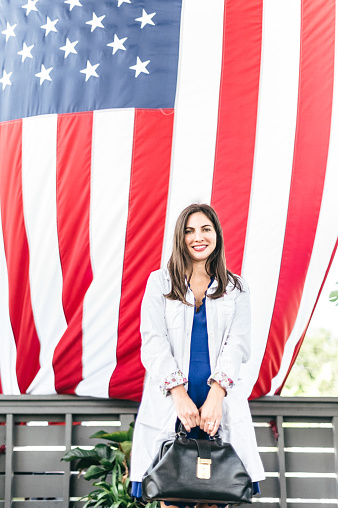 Real licensed female medical doctor poses in front of American flag