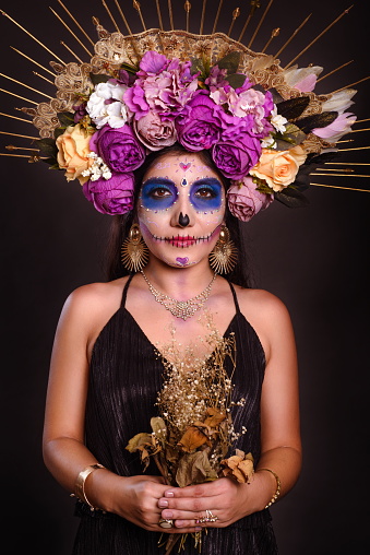 Studio portrait of a girl with catrina makeup. Day of the dead and halloween character with dark background.