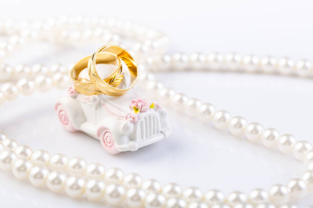 dos anillos de boda en un pequeño coche de época con collar de perlas. - pearl jewelry wedding necklace fotografías e imágenes de stock