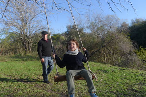 grandfather swinging his grandson in the field