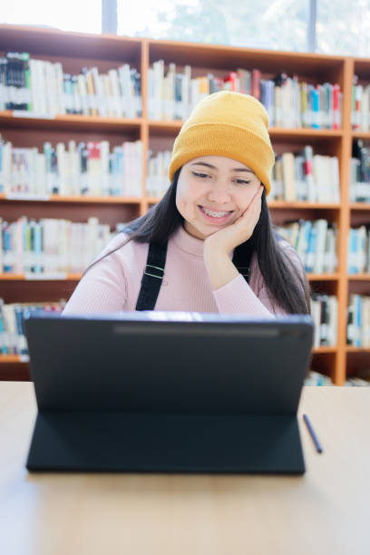 College space: Front view of Young Smiling Female University Student Studying with her Tablet at the Library