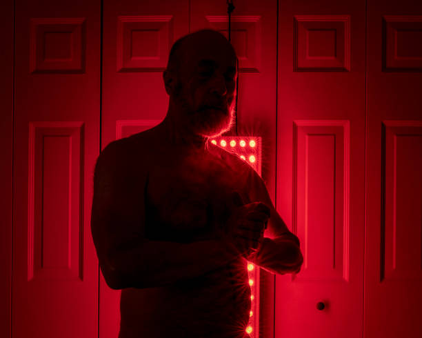 istock silhouette of a senior athletic, man torso standing in front of the red light therapy panel, home setup for treatment 1614955202