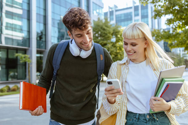 istock Cheerful students using smart phone on the street 1614978875