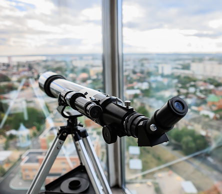 Telescope at the window aimed at the city
