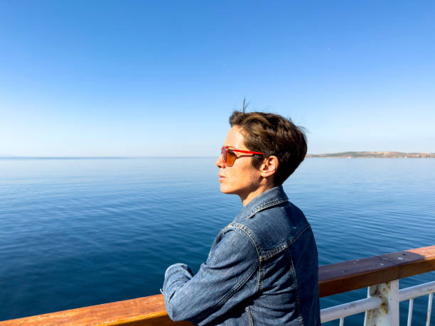 A beautiful woman is leaving Bozcaada on a passenger ferry. She looks peaceful and happy, she. Sunny morning.
