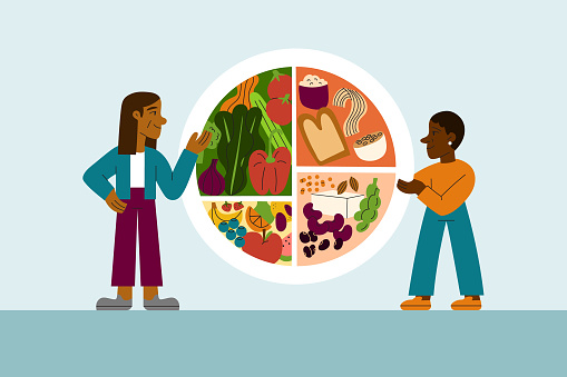 A woman dietician teaches balanced healthy vegan eating to a young black woman using a plate infographic