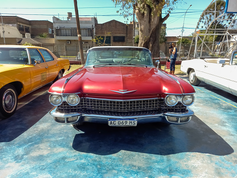 Lanus, Argentina - Sept 24, 2022: Old red luxury 1960 Cadillac coupe DeVille in a park. Sunny day. AAA 2022 classic car show.