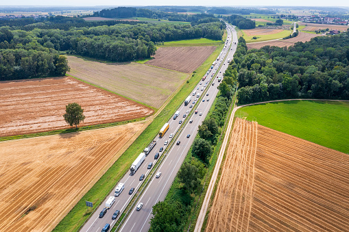 A long lane of cars and trucks standing in a traffic jam on a highway viewed from above.
