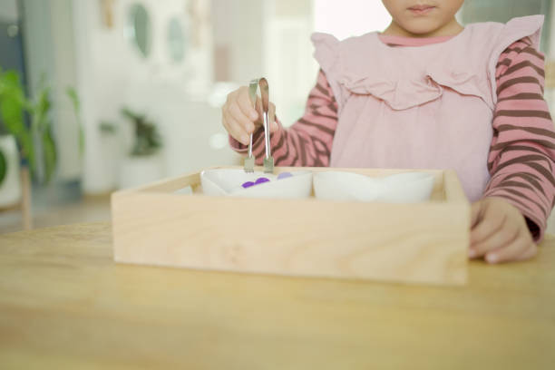 istock Preschool mixed girl transferring pom-pom with tong, practical life skill activity, preliminary exercises in Montessori education school 1615091147