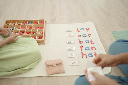 Elementary girl learning words and phonetic spelling using moveable alphabet in Montessori education school and homeschooling