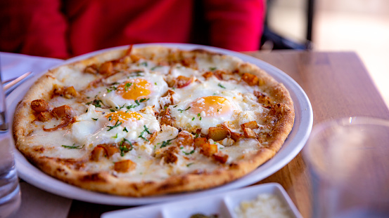 I enjoyed a delicious breakfast pizza topped with gooey cheese and crispy bacon, perfectly complemented by a sunny side up egg on top.
