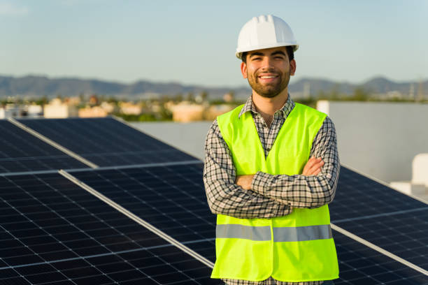 istock Happy solar panel installer with a green vest and safety helmet 1615145460