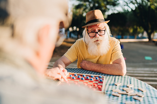 Senior man playing checkers with a friend in the park