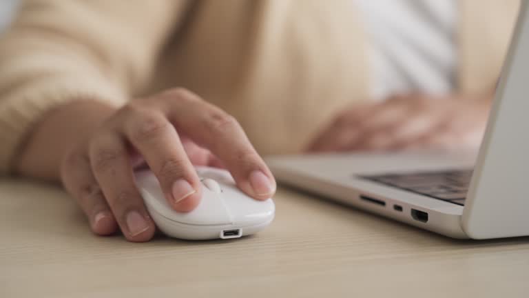 Young woman hand clicking and using computer mouse working on a laptop