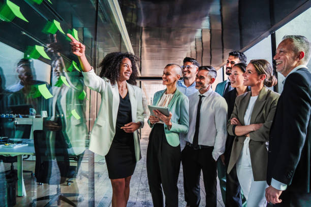 groupe de gens d’affaires démarre le travail d’équipe en utilisant le poster au bureau lors d’une réunion de collaboration heureuse. femme d’affaires expliquant la nouvelle stratégie ou le nouveau plan marketing à ses collègues - innovation photos et images de collection