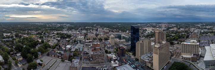 The skyline of Lexington, Kentucky, featuring the financial business district in the foreground and the University of Kentucky campus in the distance, illuminated by a cloudy sunrise.
