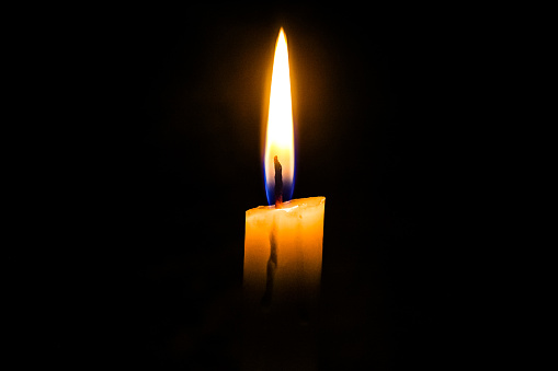 a burning candle, in the dark