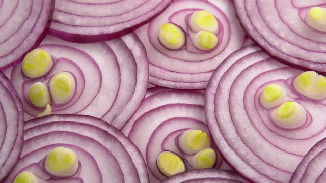 Sliced red onion rotates as background for cooking show, restaurant or food video. Sliced shallot rings close-up. Top view of food healthy background with vegetable of rich vitamin
