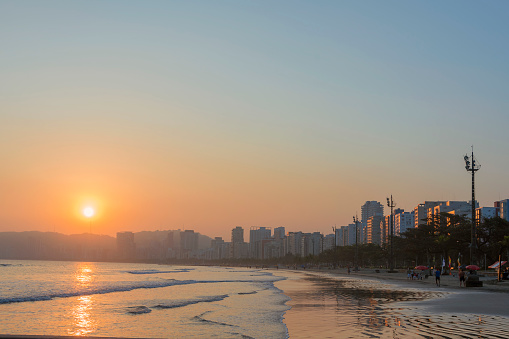 City of Santos, Brazil. People enjoying the sunset on the edge of Boqueirão beach. In the background the waterfront buildings.
