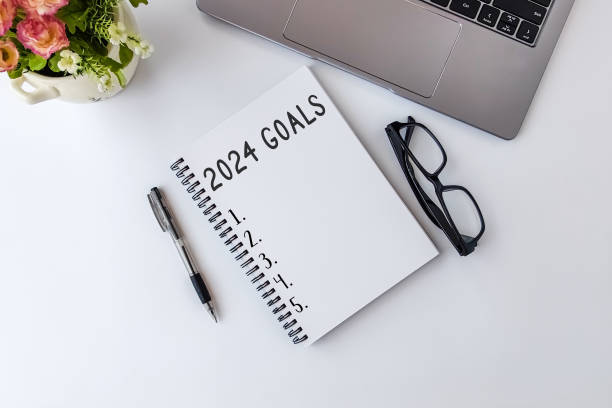 Top view of notebook handwriting goals for 2024 year. Top view of notebook handwriting goals for 2024 year, laptop and eyeglasses on white background. Business plan concept. new year resolution stock pictures, royalty-free photos & images