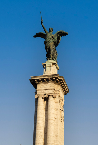 Winged Victory statue on the column, at the entrance to the Vittorio Emanuele II bridge in Rome, Italy