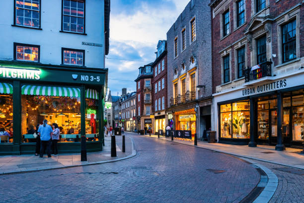 People stand next to a restaurant in downtown Cambridge, Cambridgeshire, England, UK in the evening.