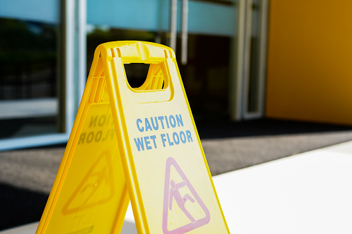 Yellow wet floor caution sign in wet corridor