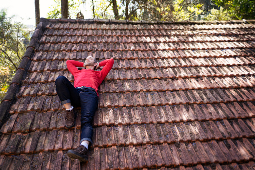 Non binary person with autism lying on tiled roof