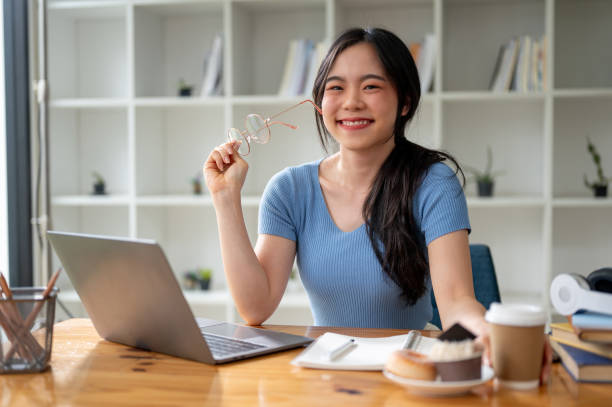 istock A happy Asian female college student sits at her study table at home. 1615617314