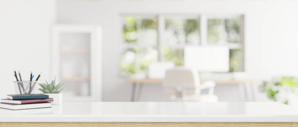 istock Copy space on a white tabletop in a modern white office room. 1615624297