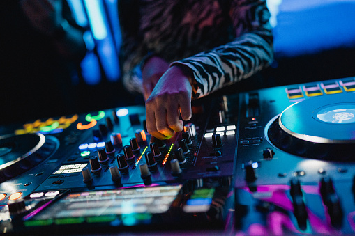Close up of DJ hands controlling a music table in a night club.