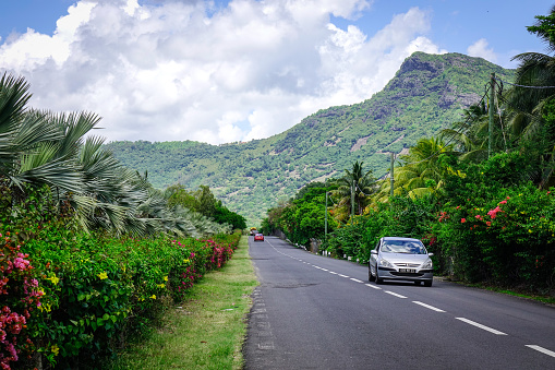 Le Morne, Mauritius - Jan 5, 2017. Cars running on rural road in Le Morne, Mauritius. Mauritius was uninhabited until 1598, and had much unique wildlife and plant life.