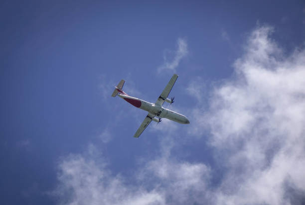 A small commercial jet coming in for a landing, landing gear down at a regional airport