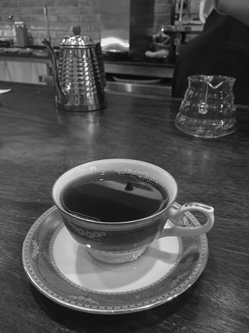 Hot black coffee in ceramic cup on the wooden table