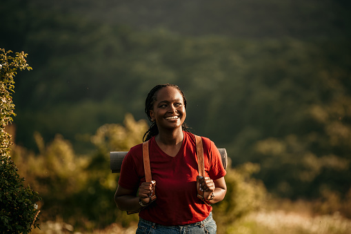 With her hiking gear and backpack, a black woman confidently climbs the hills, glancing at her phone to ensure she stays on the right path indicated on the map.