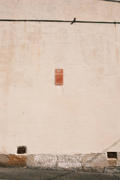 Red metal No stopping sign on an old faded wall.