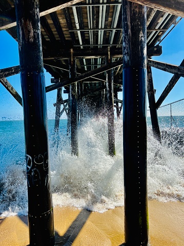 An image of a wave crashing under the famous Seal Beach Pier.