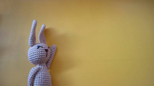 istock Crocheted rabbit on the white cloth background. Knitted toy, handmade, needlework, bunny amigurumi. 1615729109