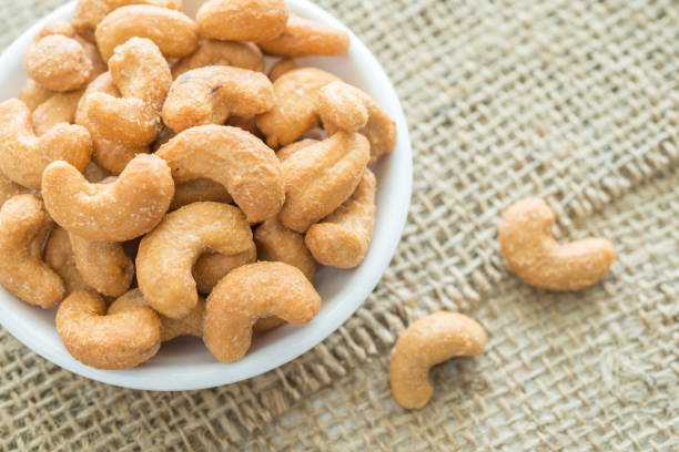 istock Salted cashew nuts in dessert bowl on sackcloth background. 1615771087